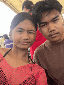 a boy and a girl are posing for a picture and the girl is winking