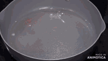 a man in a blue shirt is pouring a bag of food into a frying pan on a stove top ..