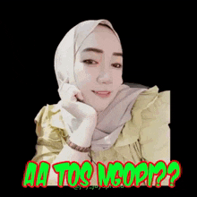a woman wearing a hijab and a green shirt is smiling and looking at the camera .