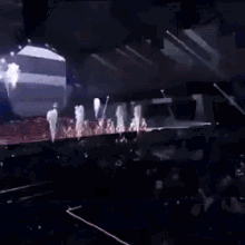 a group of people are dancing on a stage with smoke coming out of them .