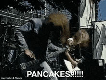 a man is playing a guitar on a stage and the words pancakes are on the screen .