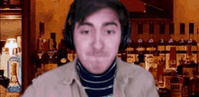 a man wearing headphones is standing in front of a bar full of bottles of alcohol .