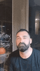 a man with a beard is standing in front of a window with the word merry written on it ..