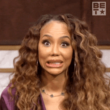 a woman with curly hair is making a funny face while wearing a necklace .