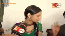 a woman in a green dress is talking into a microphone with e24 written on it
