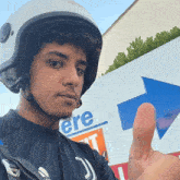 a man wearing a helmet is giving a thumbs up
