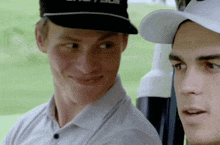 two men are sitting in a golf cart and one of them is wearing a hat that says ' taylor ' on it