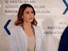a woman in a lab coat stands in front of a sign that says acil radyolo