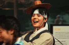 a man wearing a straw hat and a bandage on his head smiles