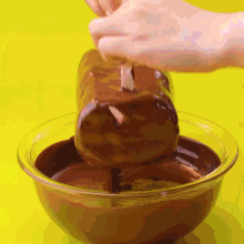 a person dipping a piece of chocolate in a bowl of chocolate