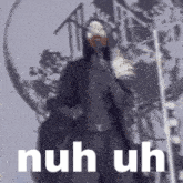 a man in a hooded jacket is standing in front of a building with the words nuh uh written on the bottom