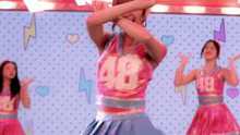a group of cheerleaders are dancing on a stage in front of a lightning bolt and hearts .