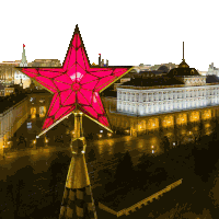a red star on top of a gold tower with a building in the background