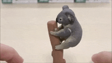 a toy koala bear is climbing a tree stump .