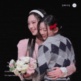 two girls hugging each other with a bouquet of flowers in their hands