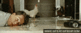 a man is laying on the floor with a chicken standing next to him .
