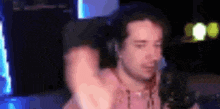 a man without a shirt is sitting in front of a microphone in a room .