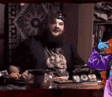 a man with a beard is sitting at a table with a teddy bear in front of him