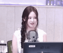 a woman is sitting in front of a microphone and a computer screen .