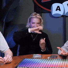 a woman sitting at a table with a stack of cards and a dice that says ' a ' on it