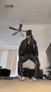 a person is dancing in a living room with a ceiling fan