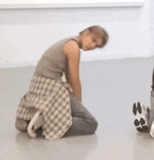 a man in a plaid shirt is kneeling on the floor .