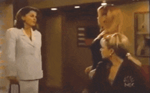 a woman in a white suit stands next to two other women