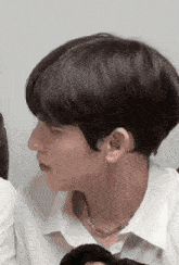 a close up of a person 's face with black hair and a white shirt .