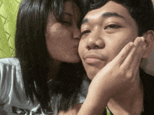 a woman kisses a man on the cheek while wearing a shirt that says levis