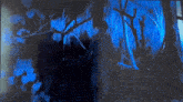 a dark room with a blue light behind a tree