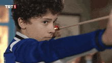 a young boy shoots a bow and arrow with a trt1 logo on the bottom