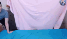 a man is laying on a blue blanket with a pink sheet covering him .