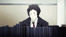 a man in a suit and tie is sitting behind a stack of books