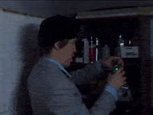 a man in a suit is reaching for a can of martini on a shelf