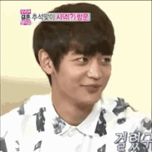 a young man is making a funny face while wearing a shirt with a pattern on it .