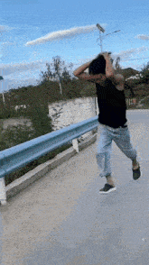 a man is running down a road with his hands on his head