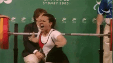 a woman squatting with a barbell in front of a sign that says " sydney 2000 "