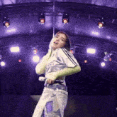 a woman wearing a shirt that says adidas on it is dancing on a stage