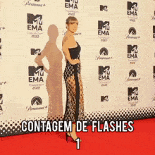 a woman stands on a red carpet in front of a wall that says mtv ema 2022
