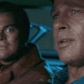 a close up of two men 's faces with one looking at the other