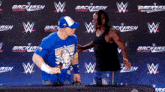 a man wearing a blue shirt that says " let 's go " stands next to another man