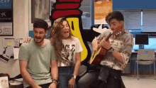 a man playing a guitar while a woman laughs
