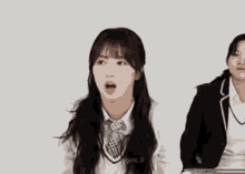 a girl in a school uniform is sitting next to another girl in a suit and tie .
