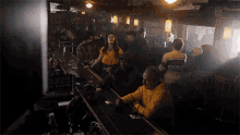 a group of people are sitting at a bar smoking cigarettes and drinking beer .
