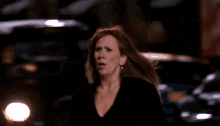 a woman with red hair and hoop earrings is walking down a street