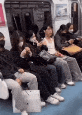 a group of people wearing face masks are sitting on a subway