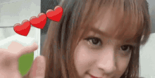 a close up of a woman holding a lollipop with three red hearts on it .