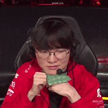 a man wearing glasses and a red jacket that says kia