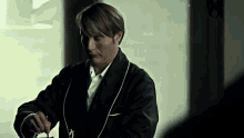 a man in a black robe is holding a knife and fork in his hand .