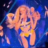 a woman is singing into a microphone on a stage while wearing a yellow and black outfit .